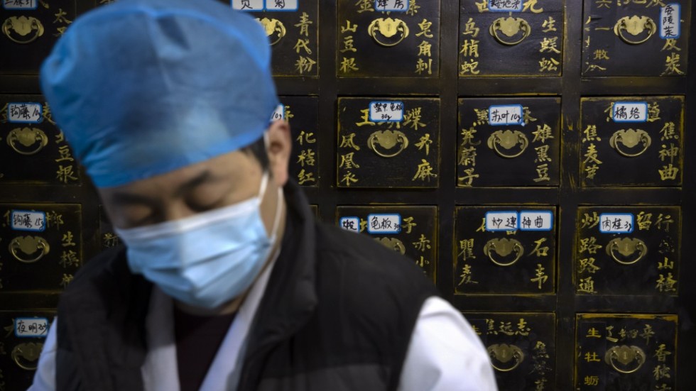 En anställd på en klinik för traditionell kinesisk medicin i Peking står framför förvaringsskåp med medicinalväxter. Bilden är från i mitten av mars.