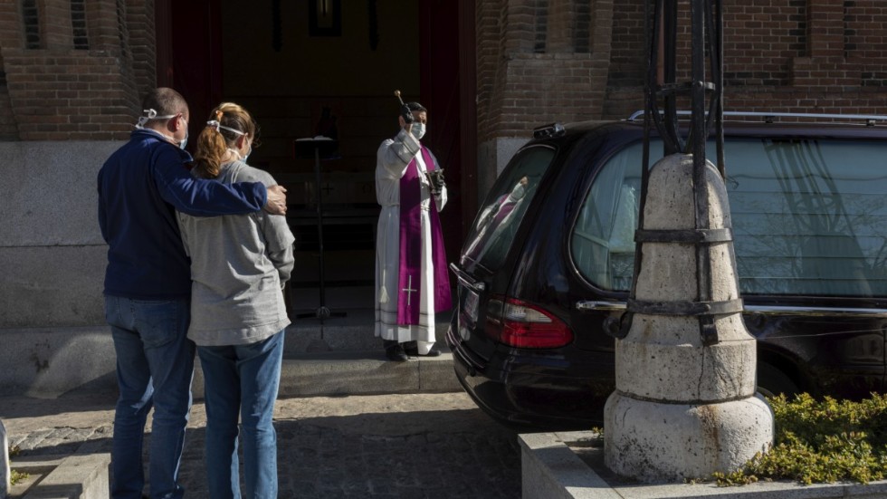 En präst genomför en begravningsceremoni på en av Madrids kyrkogårdar.