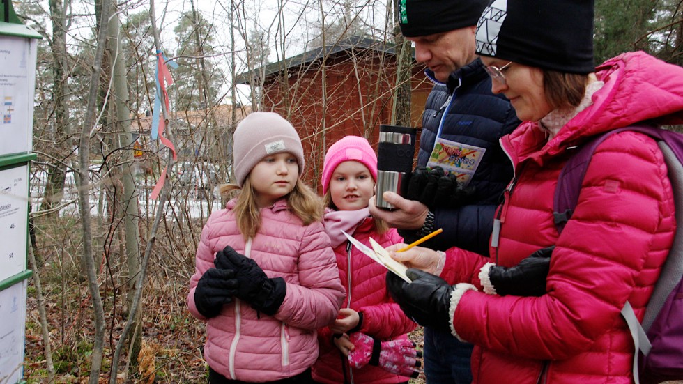 Louise och Ebba Eklund med pappa Fredrik Andersson och mamma Eva Eklund vid naturstigens första fråga, hur ser sverigefinska flaggan ut? 