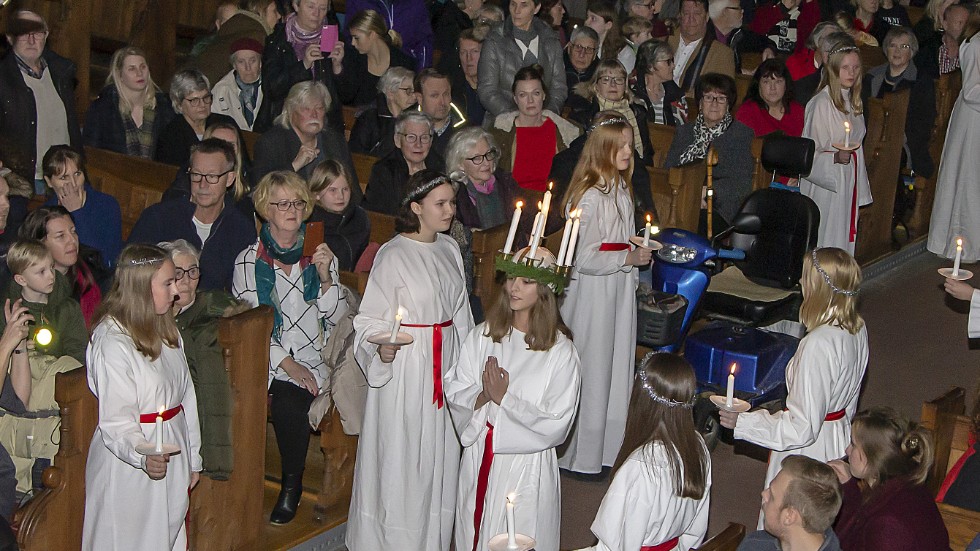 Vadstenas lucia Stina Holmstedt skrider fram i kyrkans mittgång, eskorterad av sina tärnor.