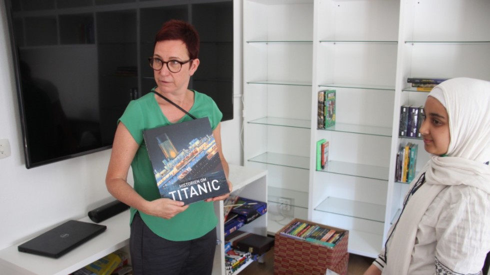 Helena Gille, bibliotekarie och samordnare på kommunen, visar Alaa en bildboksversion av Titanic.  
