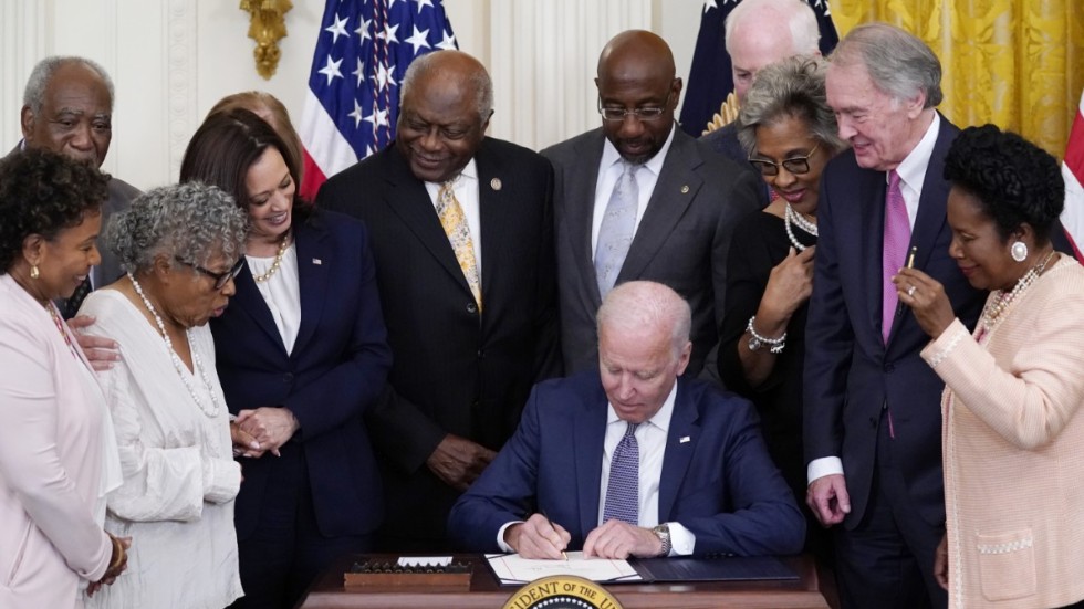President Joe Biden skriver under lag om att göra 19 juni till nationaldag. Han omgärdas av kongressledamöter.
