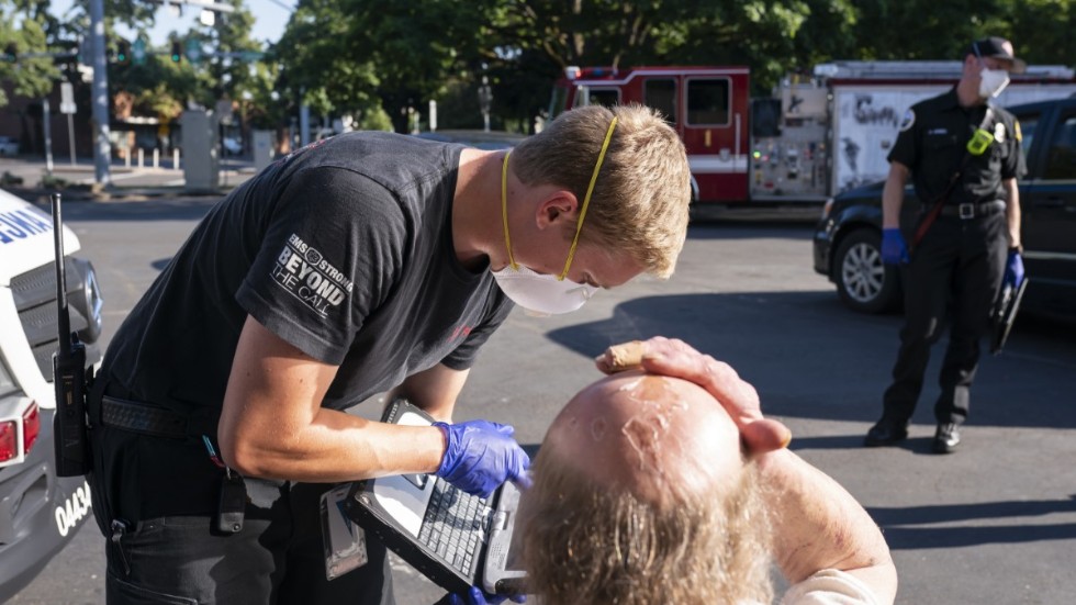 En ambulanssjuksköterska undersöker en man i Salem i Oregon, USA, under den pågående värmeböljan i västra Nordamerika.