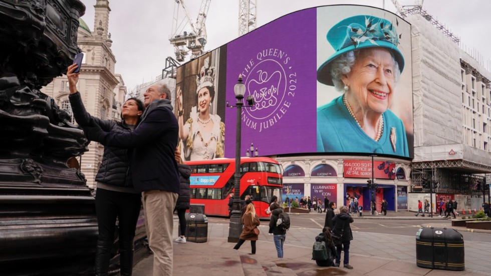 Ett par på Piccadilly Circus i centrala London tar en selfie med drottningfirandet som bakgrund.