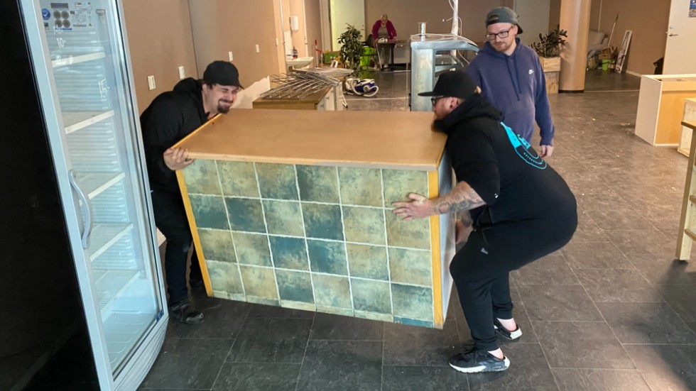 Percy Olsson och Robin Klase bär ut en tung bänk från det som förut var Kryddans the och kaffehandel i centrala Finspång. 