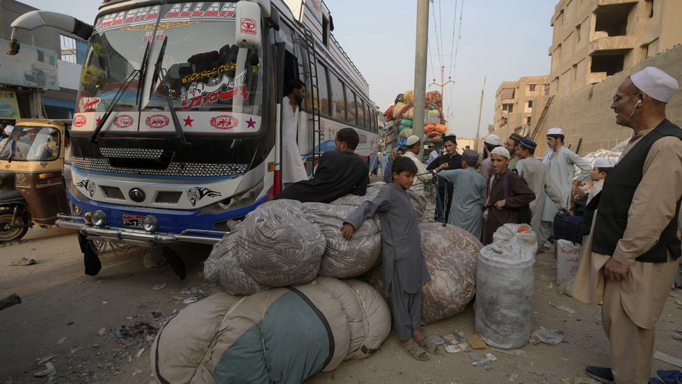Flyktingar samlas vid bussar som ska avgå mot Afghanistan i den pakistanska storstaden Karachi.