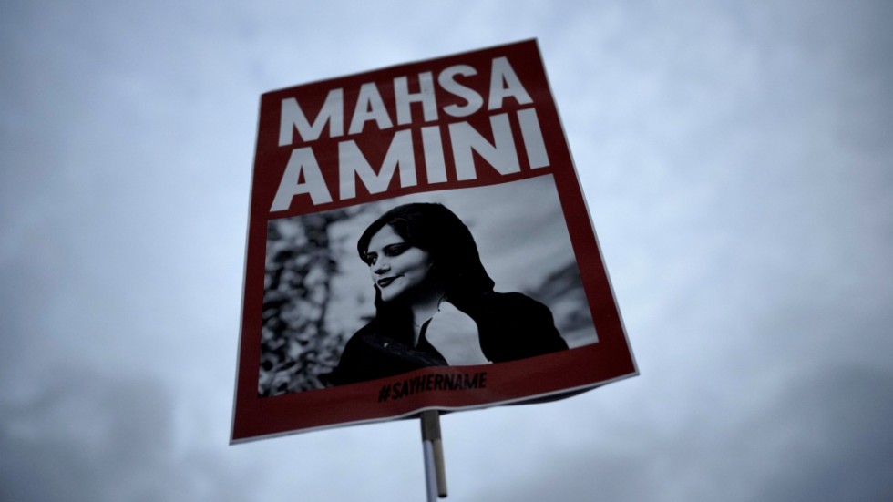 En demonstrant i Berlin håller upp ett plakat med en bild på Masha Amini som dog efter att ha gripits av Irans moralpolis för nästan ett år sedan. Arkivbild.