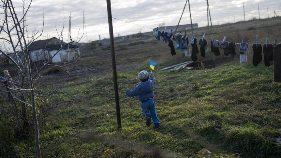 Ett barn leker med en ukrainsk flagga i utkanten av Cherson i södra Ukraina i november 2022.