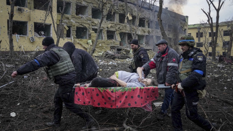 Ukrainska räddningsarbetare bär iväg en skadad och gravid kvinna från den attackerade förlossningskliniken i Mariupol, den 9 mars förra året. Arkivbild.