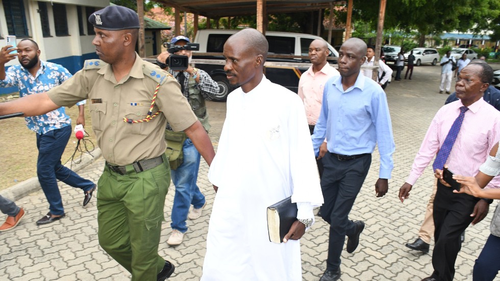 Ezekiel Odero, en av två åtalade sektledare, håller i en bibel medan han eskorteras av polis i Mombasa, Kenya.