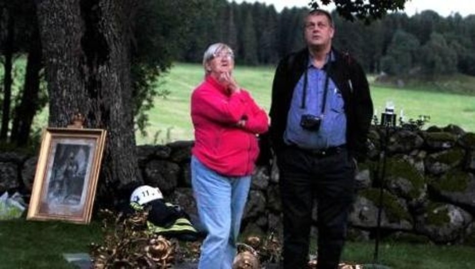 Kyrkoherde Anders Grape och en okänd församlingsbo tittar oroligt upp mot den brinnande kyrkvinden. Bakom dem ligger en del av de värdefulla invnetarier som bars ut.