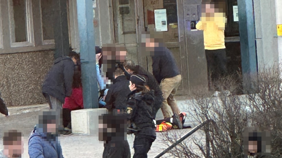 Den skadade polismannen tas om hand efter knivattacken vid polishusets etnré den 27 februari i år.