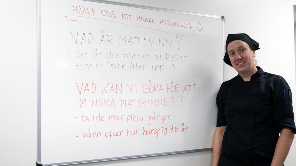 Arbetsledare Heidi Karlsson vid tavlan mitt emot disken som informerar om matsvinn.