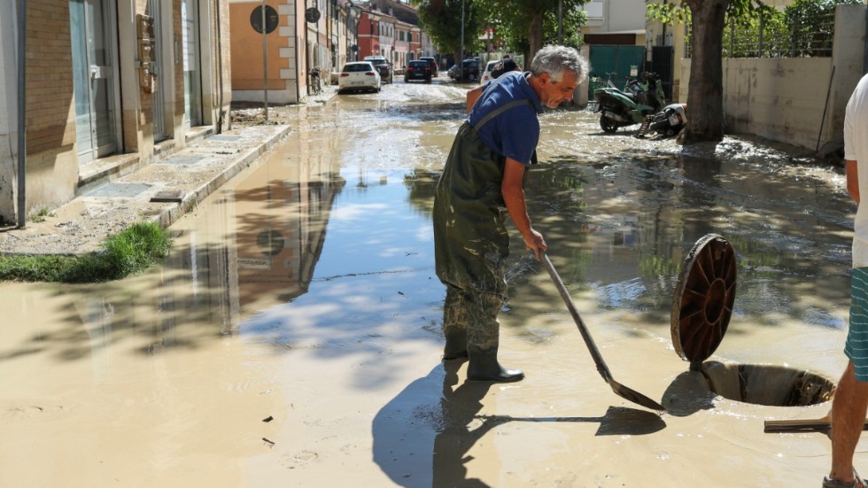 Senigallia-bon Marco Lorezetti skyfflar ned lervatten i en brunn efter de kraftiga skyfallen.
