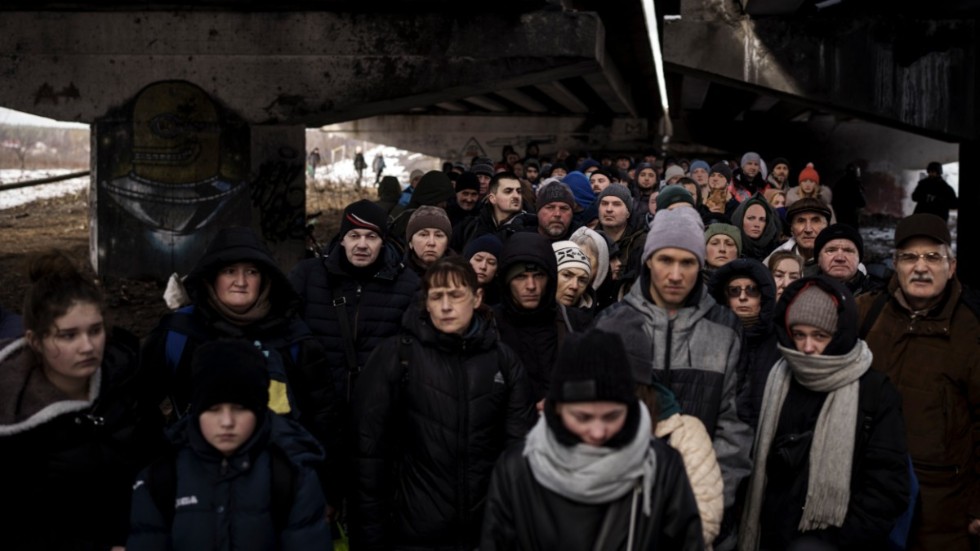 Ukrainska flyktingar samlade under en förstörd bro i närheten av Kiev.