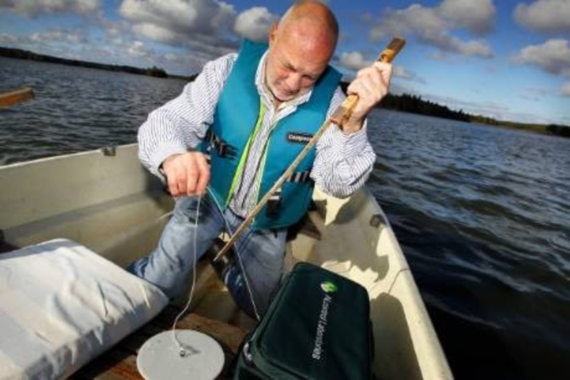 Willy Holmberg har rott ut mitt på sjön för att ta prover. Det är viktigt att mätningen görs på samma ställe varje gång. Här är det siktdjupet som kollas: 55 cm.