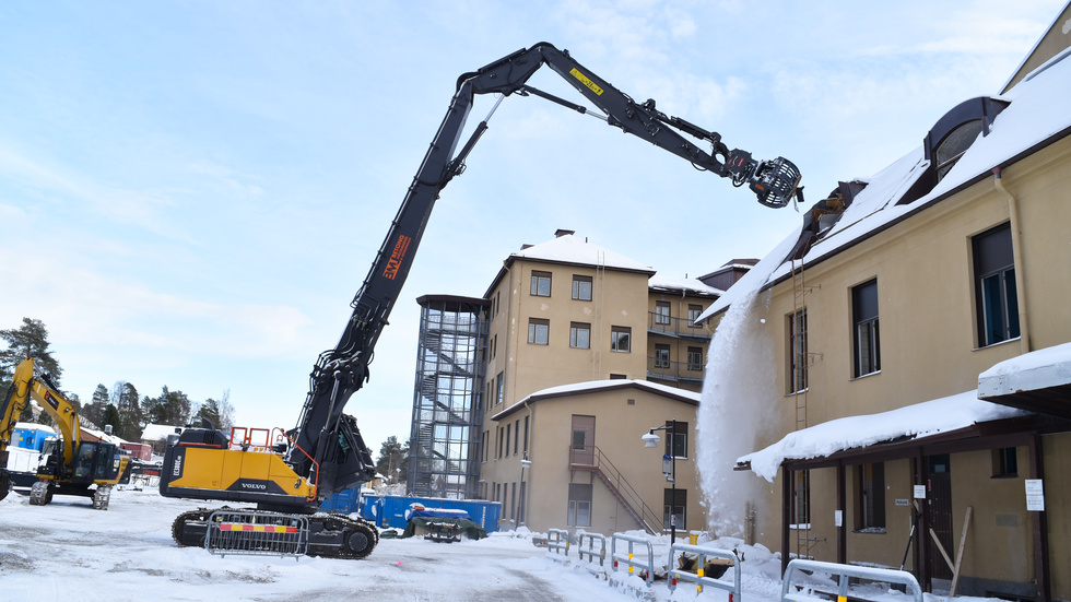 För att riva lasarettet används en högrivare som sliter loss byggnaden del för del.