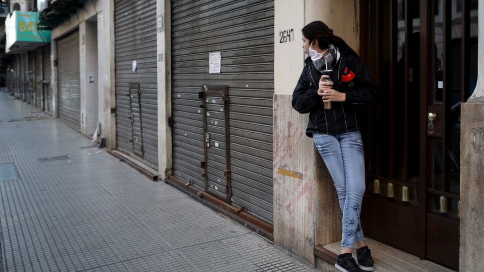 En kvinna blickar längs en gata med idel nedstängda butiker i Buenos Aires.