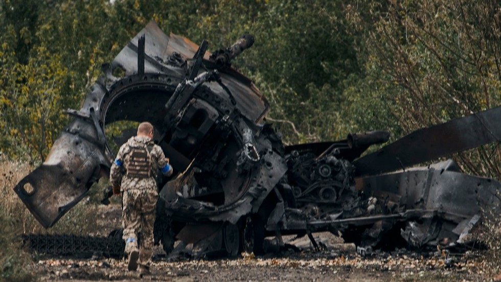 Ukrainsk soldat vid en förstörd rysk stridsvagn i nyligen återerövrade territorier i Charkivregionen.