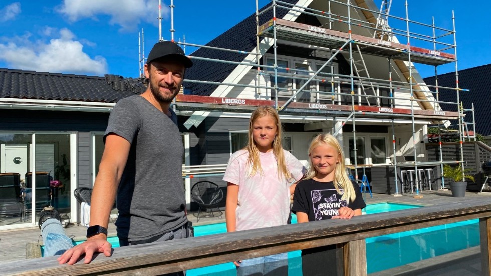 Henrik Hedberg tillsammans med döttrarna Freja och Saga framför villan som snart ska levera el via solceller. Arbetet är i full gång.