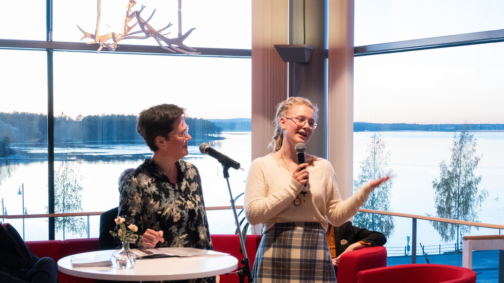 Lena Vesterlund, chef för kultur- och fritidsförvaltningen delar ut Bok & Bilds novellpris till Linnea Backman som berättar om sin novell för publiken som kommit till prisutdelningen i VIP-rummet i Kulturens hus.