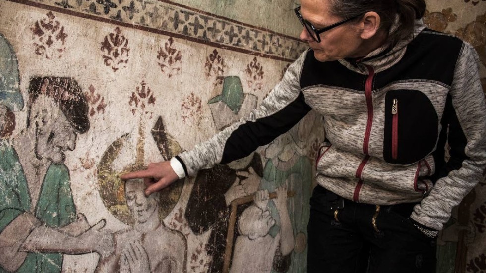 Misa Asp visar hur man fortfarande  kan se färgen som det målades med för över 500 år sedan.