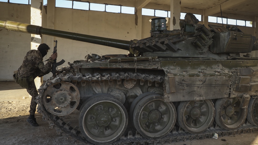 En milisman vid syrisk arméutrustning som övergivits i Maarat al-Numan nära Aleppo på lördagen.
