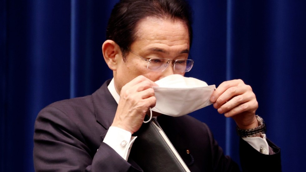 Japans premiärminister Fumio Kishida tar på sig munskydd när han lämnar tisdagens presskonferens.