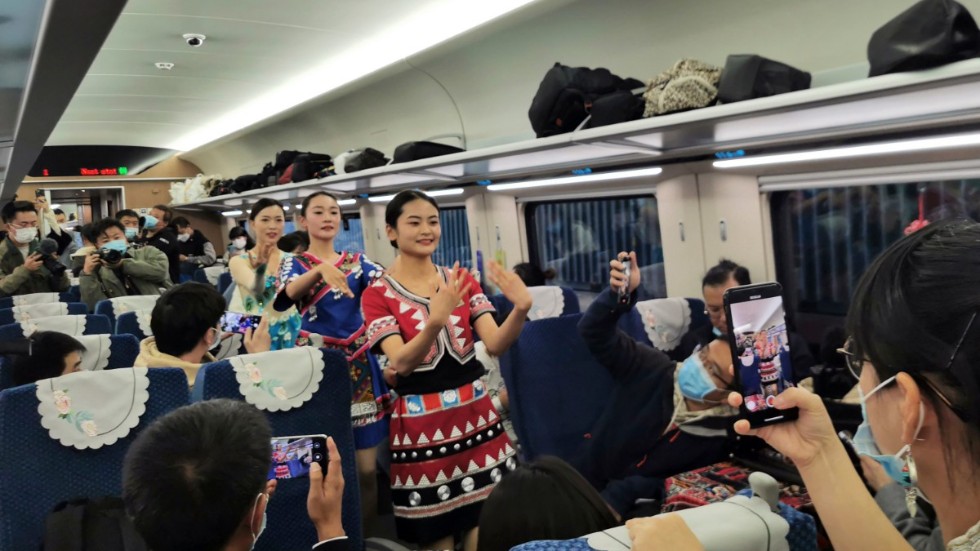 Kvinnor i folkdräkt uppträder på den kinesiska sidan gränsen för att fira trafikstarten mellan Kunming och Vientiane.