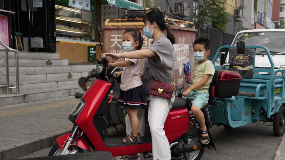 En kvinna skjutsar sina två barn i Peking i augusti 2021.