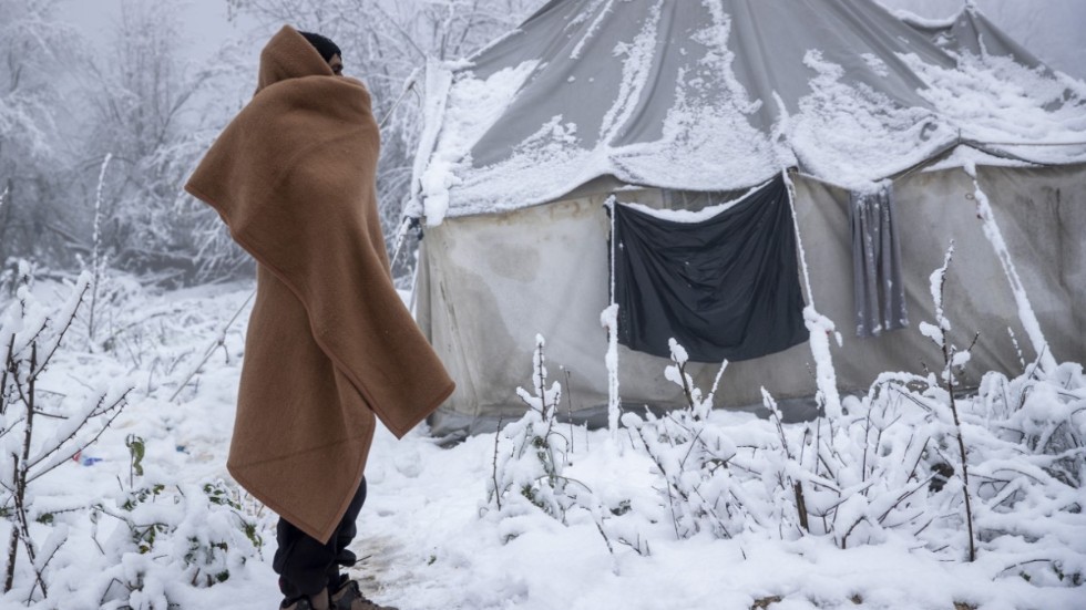 En migrant står intill ett snötäckt tält i ett läger i Vucjak, som låg inte långt ifrån där Lipalägret står, men som stängde ungefär när det öppnade. Arkivbild från 3 december förra året.