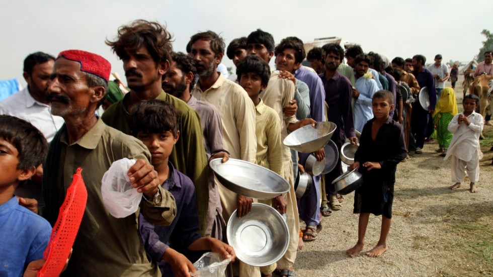 Människor som tvingats lämna sina hem köar för mat i Rajanpur i Punjab.