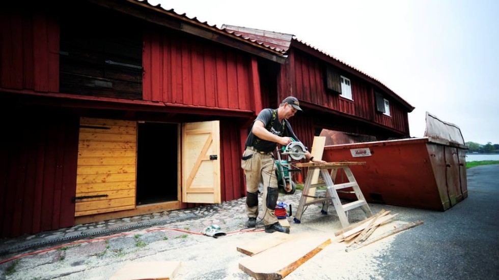 Sågar golvplankor. Lars Gustavsson arbetar med att lägga nytt golv i bodarna.