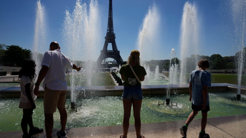 Turister svalkar sig vid fontänerna vid Eiffeltornet i Paris den 3 augusti, i 36 graders värme. Arkivbild.