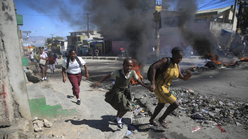 En kvinna och hennes dotter springer förbi en avspärrning på en gata i Haitis huvudstad Port-au-Prince den 26 januari.