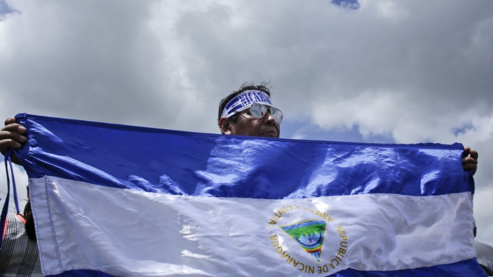 En demonstrant håller upp i flagga under en demonstration för stöd för journalister i Nicaragua 2018.