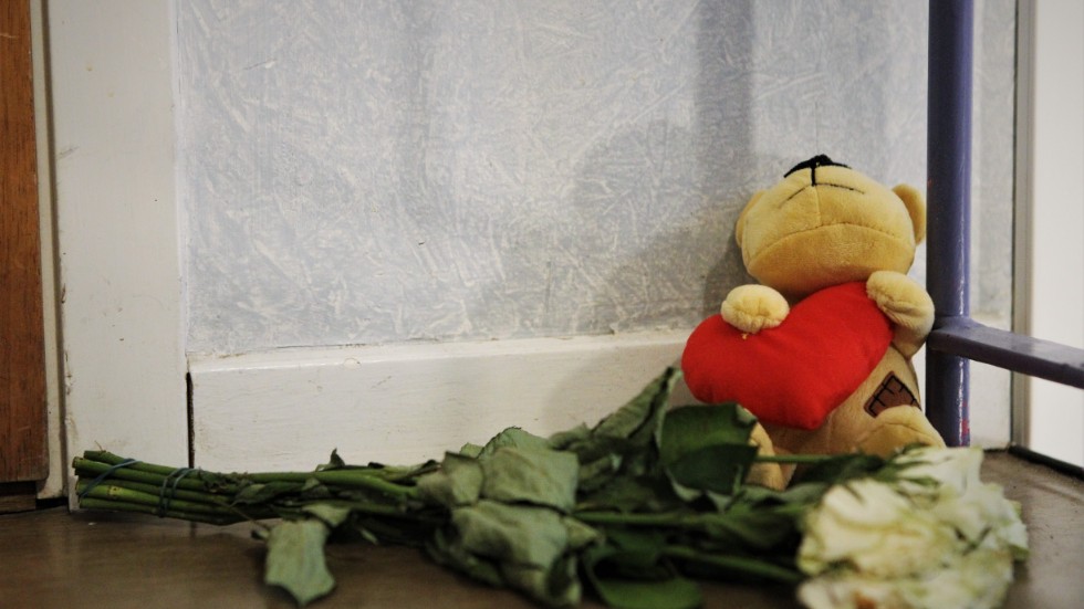 Blommor och minnesföremål har placerats invid dörren till lägenheten där den döde mannen påträffades. 