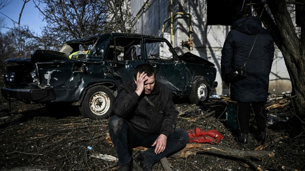 En ukrainsk man sitter utanför sitt förstörda hem efter bombningarna i östra Ukraina, i staden Tjuhuiv, morgonen den 24 februari.