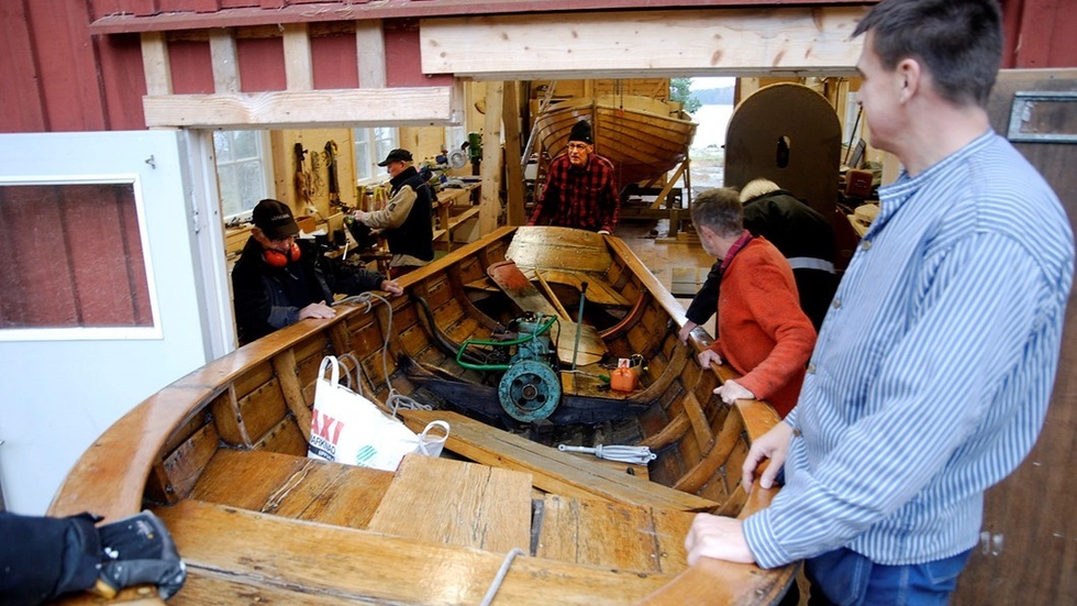 En liten trevlig ekbåt med en Albinmotor är på väg in i båtverkstan för lite översyn. Byggd av Elis Svensson på Lindnäs och skänkt till föreningen av Ingvar Flink. Till höger syns Mattias Evald och inne tar Bo Lewander emot.