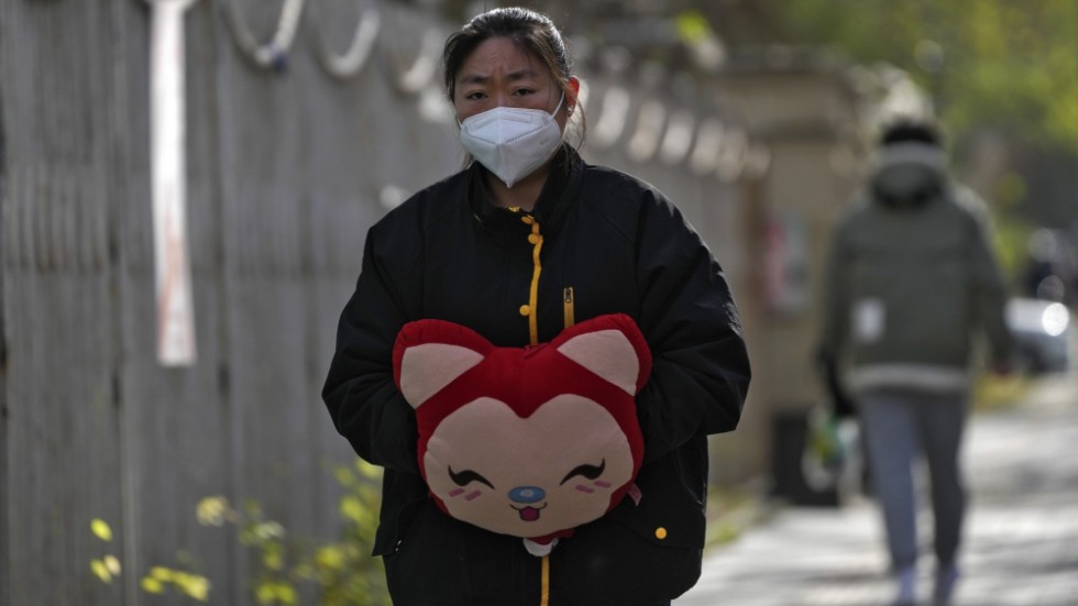 En kvinna värmer sina händer i iskylan i Peking under tisdagen. Universitet skickar hem sina studenter, och stor polisnärvaro i storstäder ska förhindra nya protester.