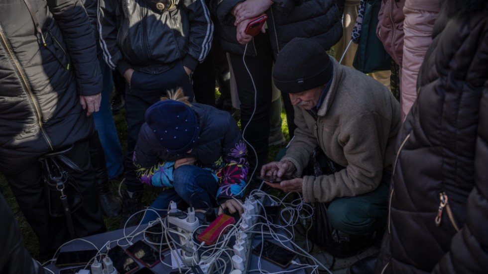 Invånare i Cherson laddar sina telefoner och försöker koppla upp sig mot internet med hjälp av en generator på stadens torg på måndagen.