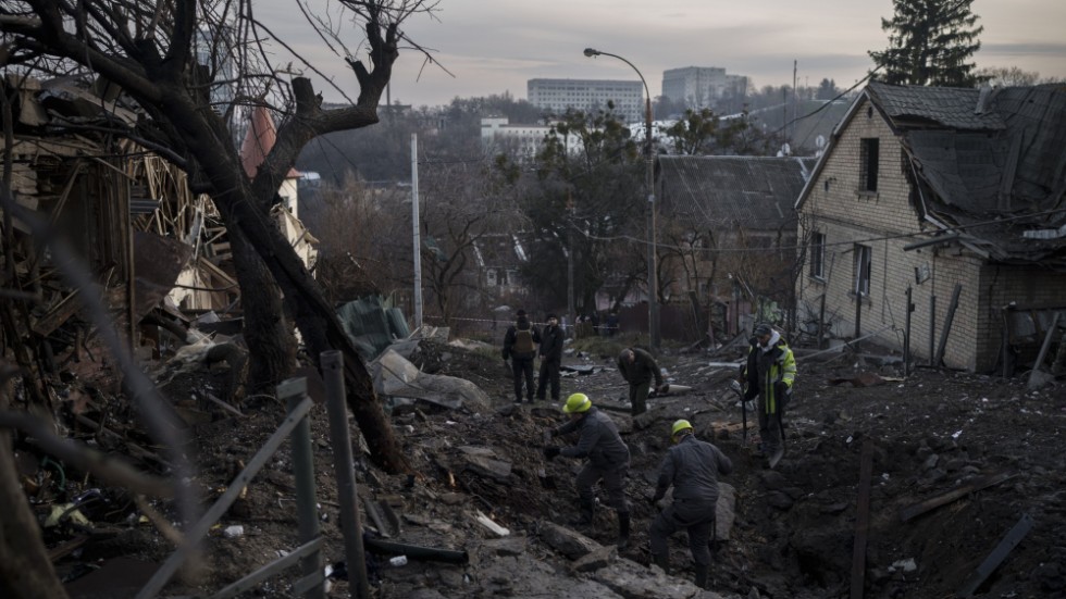 Ukrainska kommunalarbetare inspekterar en krater i Kiev efter lördagens ryska robotangrepp.