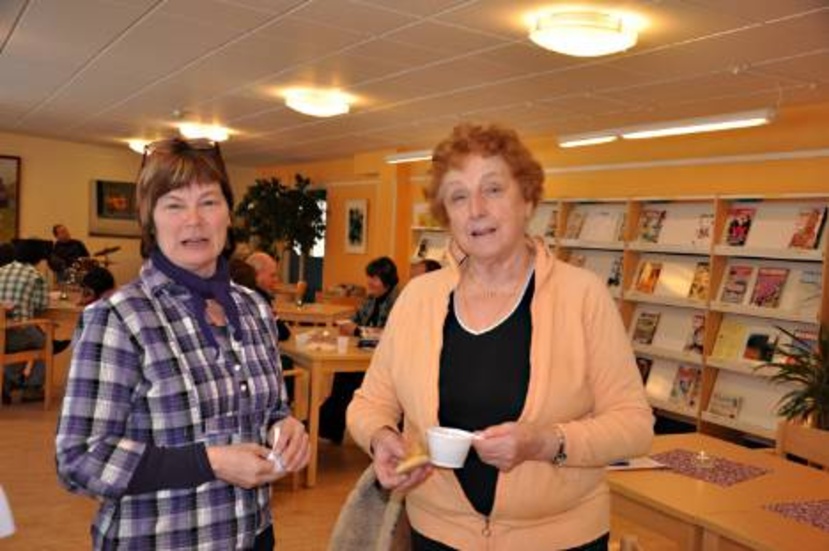 Bibliotekarien Liselotte Lagnestig välkomnar trogne besökaren Kerstin Josefsson med kaffe.