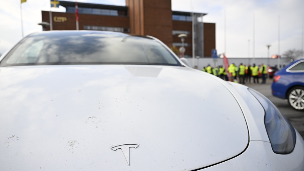 En Teslabil i förgrunden till konfliktande transportarbetare vid Malmö hamn. Arkivbild.