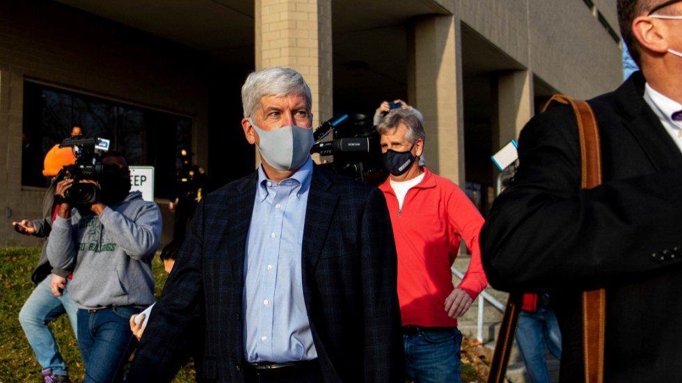 Michigans före detta guvernör Rick Snyder följs av medier i centrala Flint, efter det att han framträtt i domstol via videolänk på torsdagen.