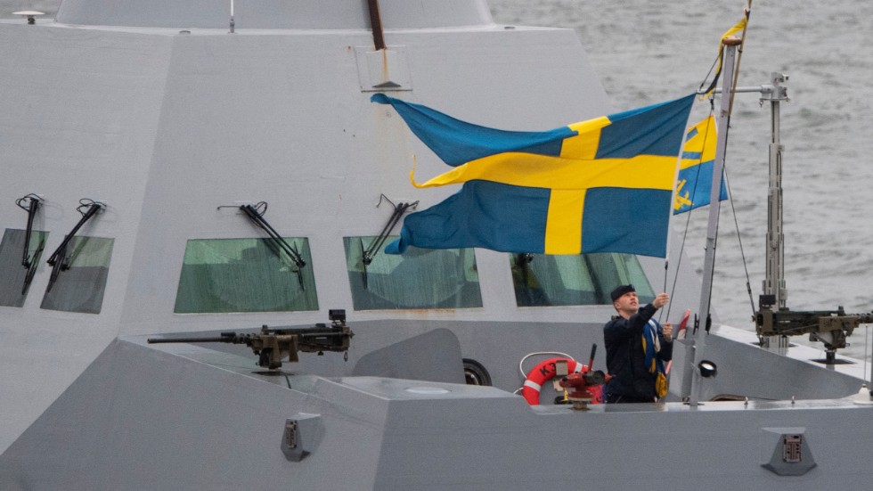 En matros på flottans korvett Helsingborg hissar den svenska flaggan.