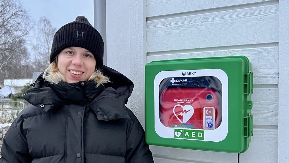 Hanna Thunvall vid hjärtstartaren, som sitter på ett hus i Målängsområdet.