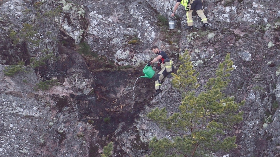 Här släcker räddningstjänsten branden med en vattenkanna.