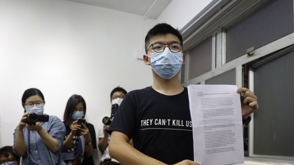 Demokratiaktivisten Joshua Wong håller upp det dokument som visar att han diskvalificerats från att ställa upp i valet som nu skjutits upp.