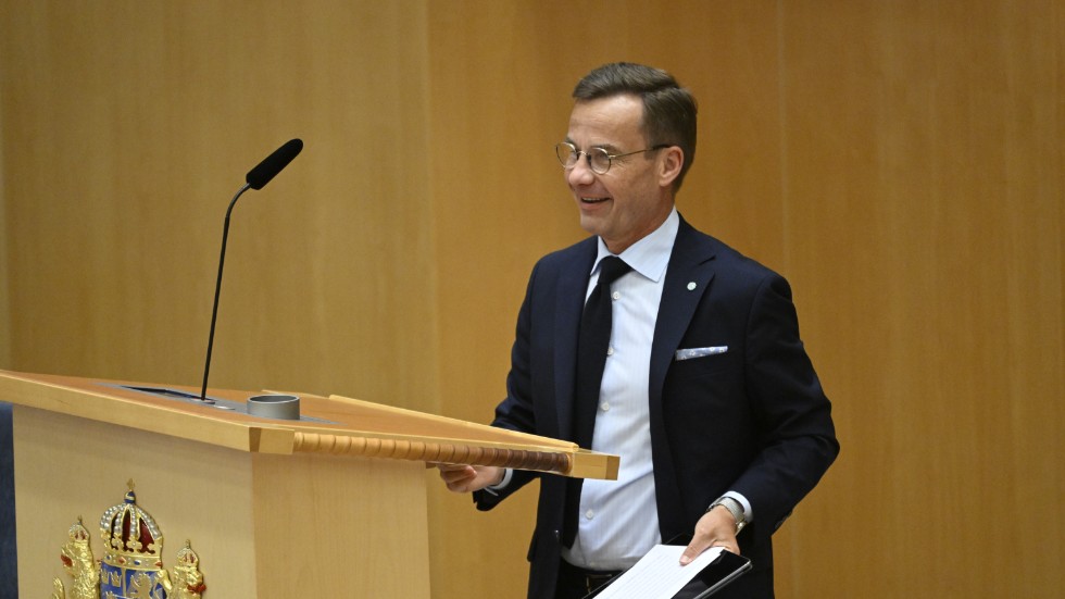 Statsminister Ulf Kristersson (M) justerar höjden på talarstolen efter att Johan Pehrson talat under partiledardebatten i riksdagen.